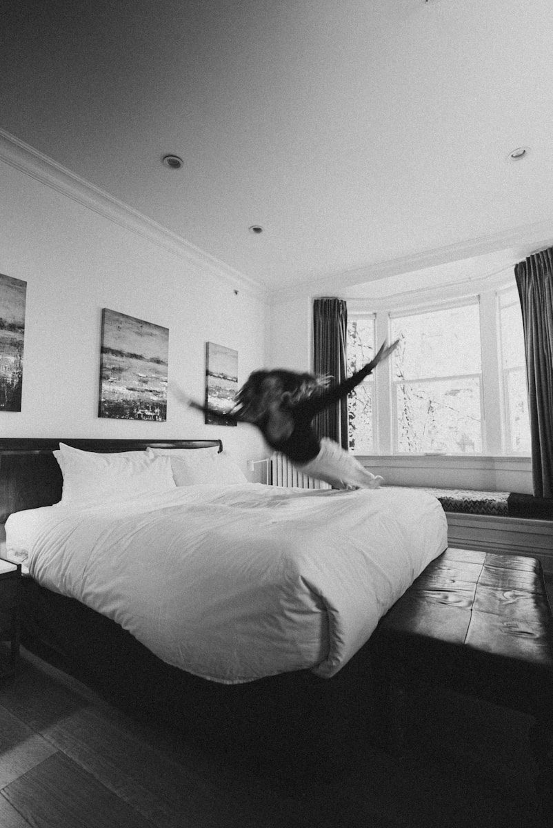 A black and white photo of a person jumping on a bed